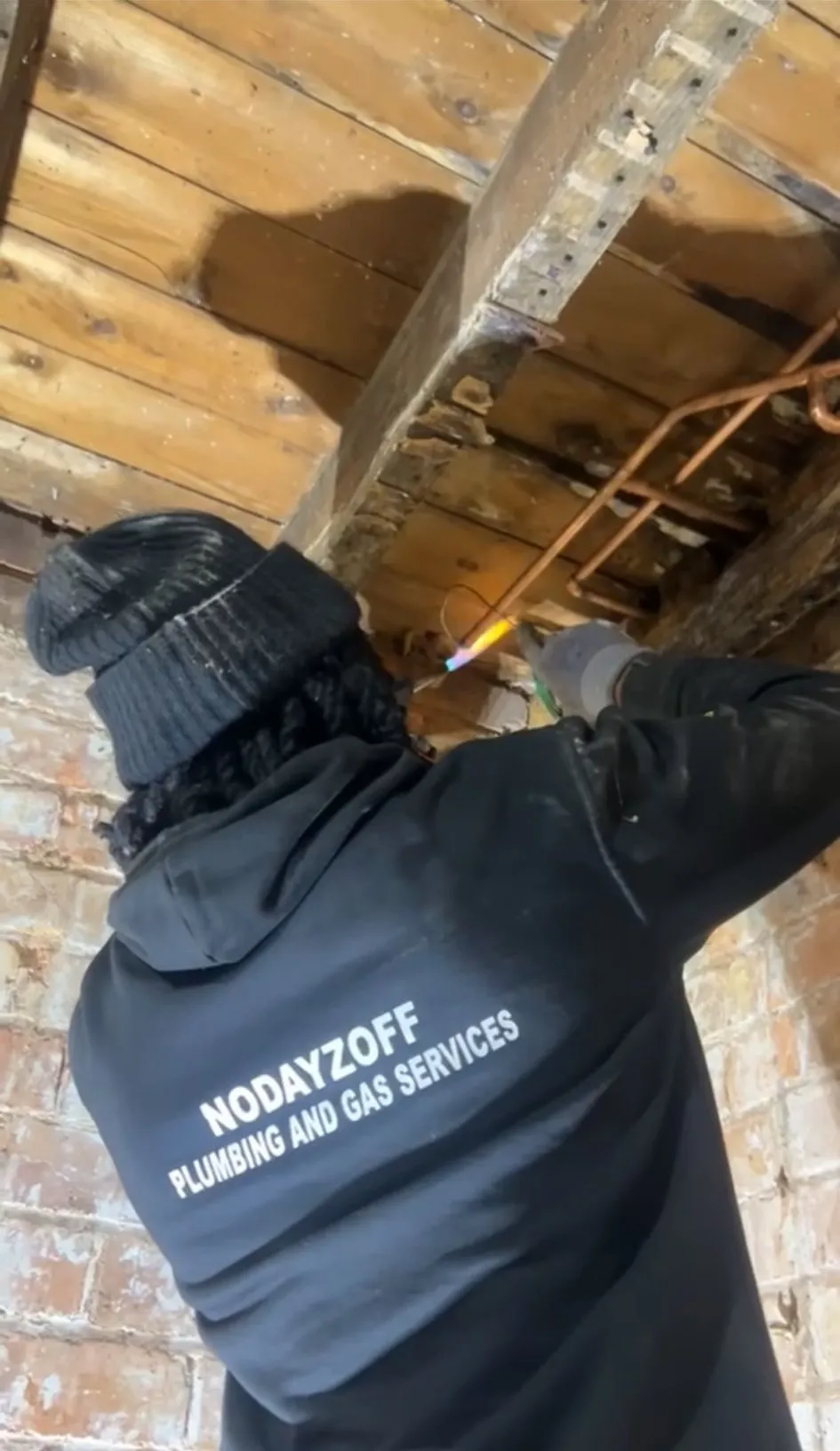 An NDO Plumbing & Gas engineer in a branded hoodie